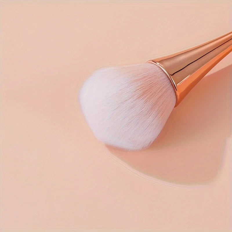 Rose gold fan brush with soft bristles, ideal for applying powder, highlighter, blush, and finishing touches