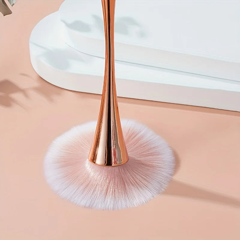 Rose gold fan brush with soft bristles, ideal for applying powder, highlighter, blush, and finishing touches